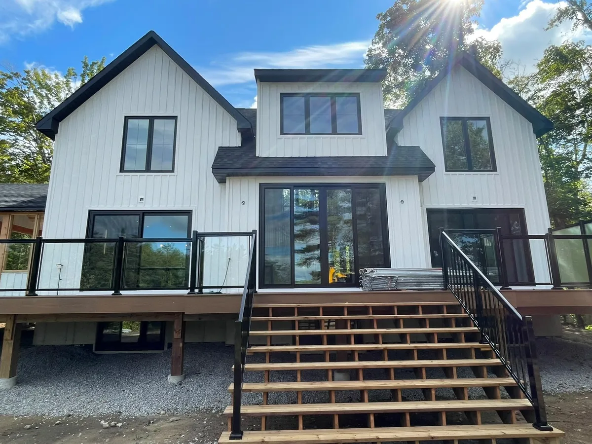 New black-frame sliding patio doors opening onto a rear deck of a white modern home, patio door installation in Vaughan