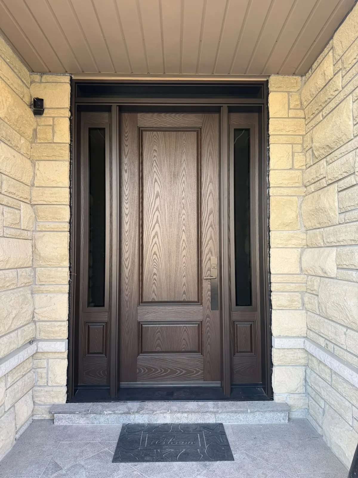Brown woodgrain fibreglass entry door with tall glass sidelites and transom in a stone entrance, fiberglass doors in Toronto