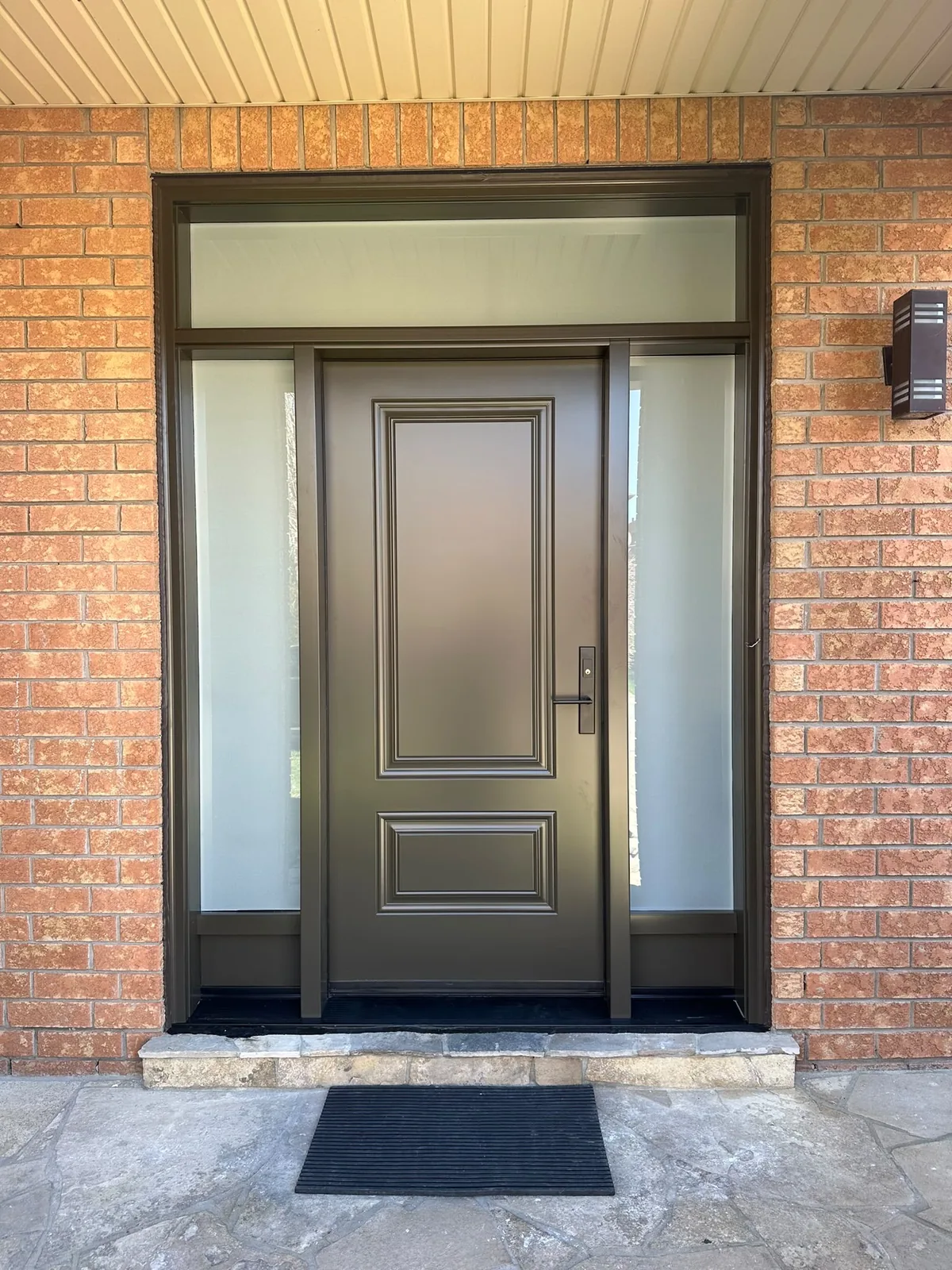 Dark brown entry door with frosted sidelites and transom in a red-brick entrance, storm door installation in Toronto